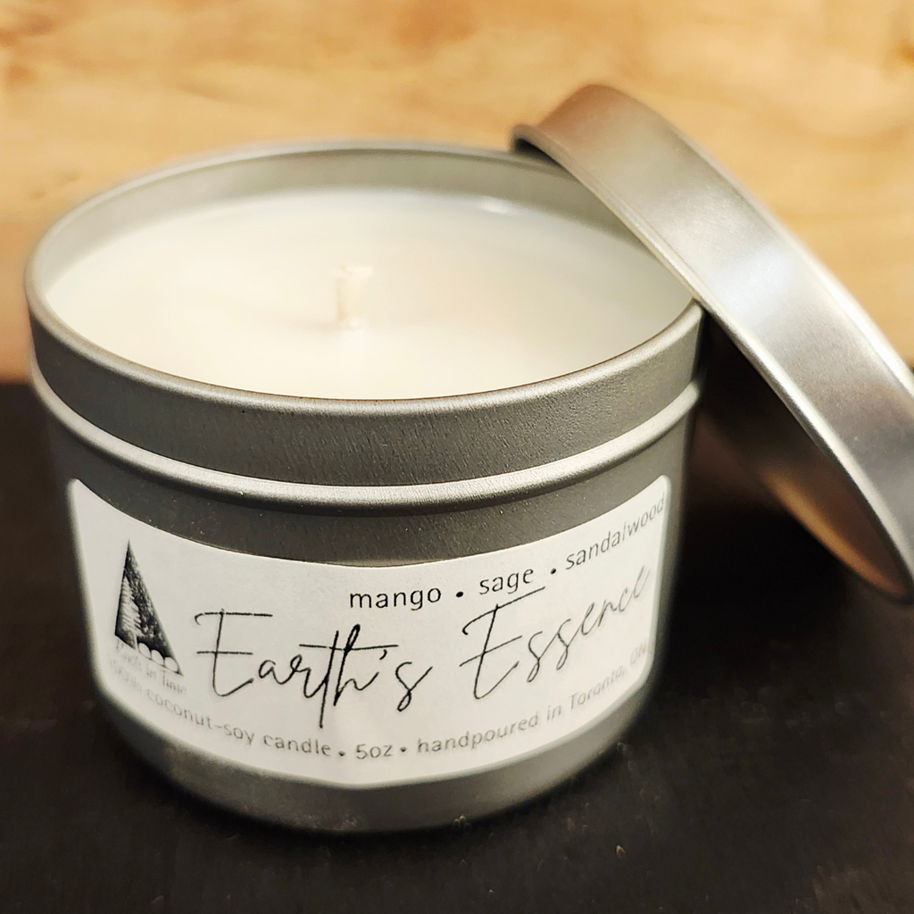 Candle in a tin labeled 'Earth's Essence' with a wooden background