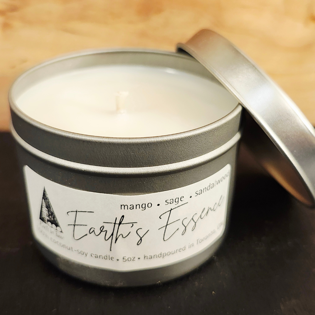 Candle in a tin labeled 'Earth's Essence' with a wooden background
