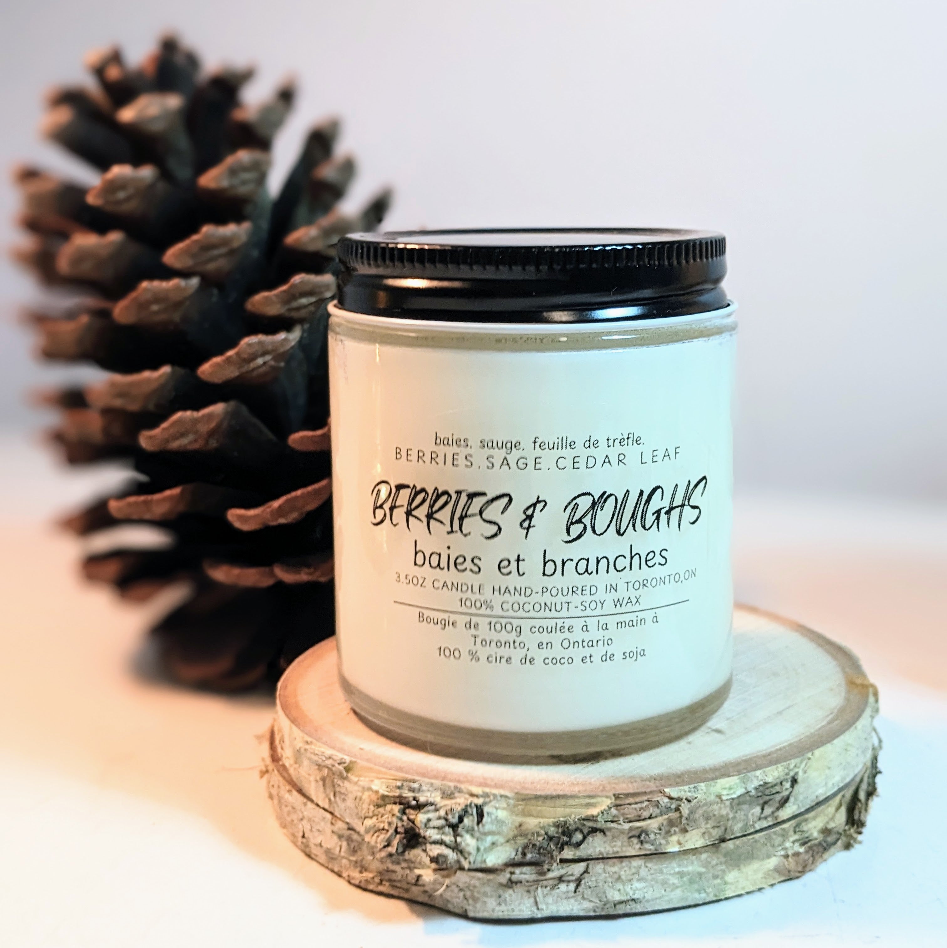 Candle labeled 'Berries & Bougns' with a pine cone on a light background