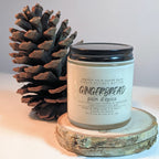Gingerbread scented candle with a pine cone on a wooden surface
