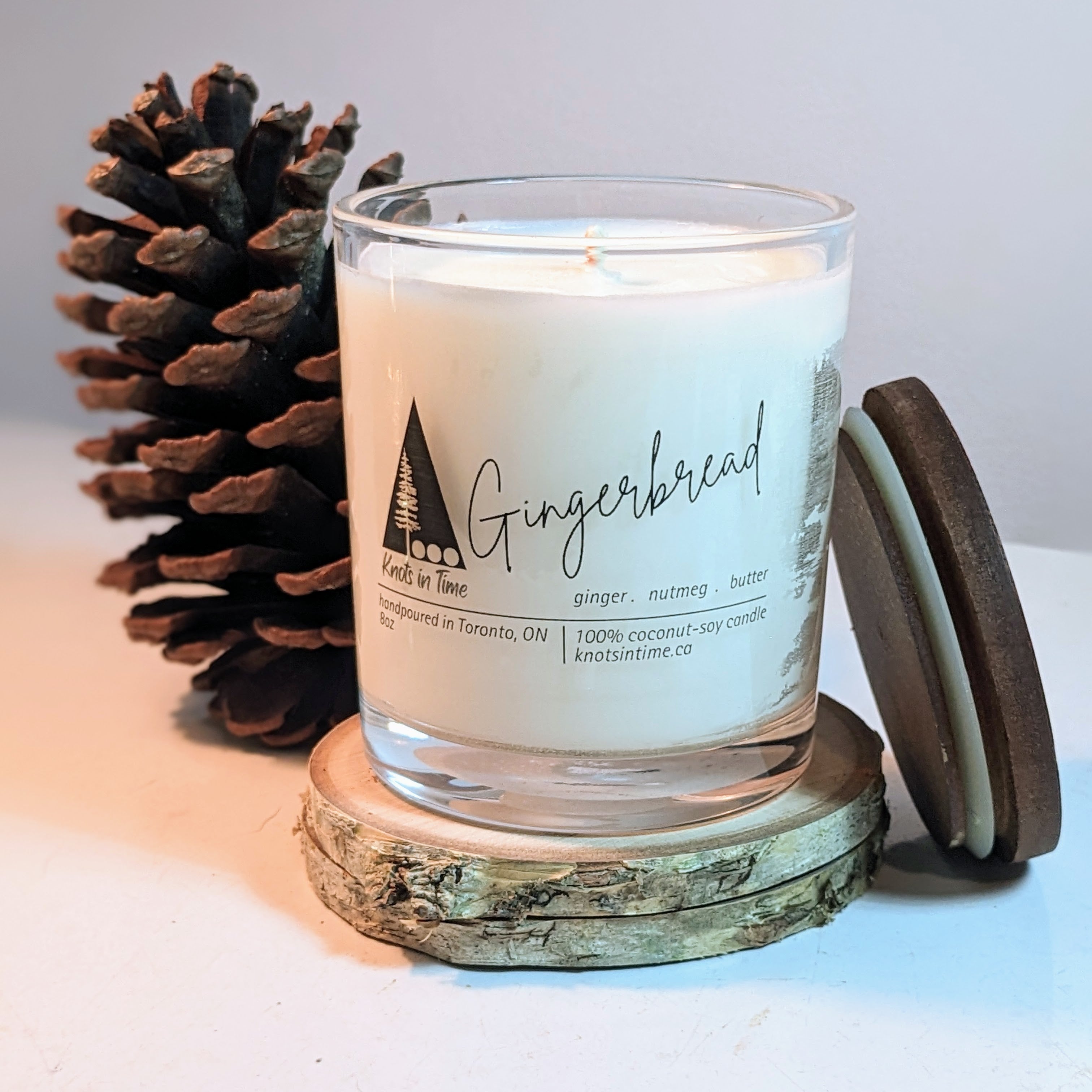 Gingerbread candle with a pine cone and wooden coaster on a light surface