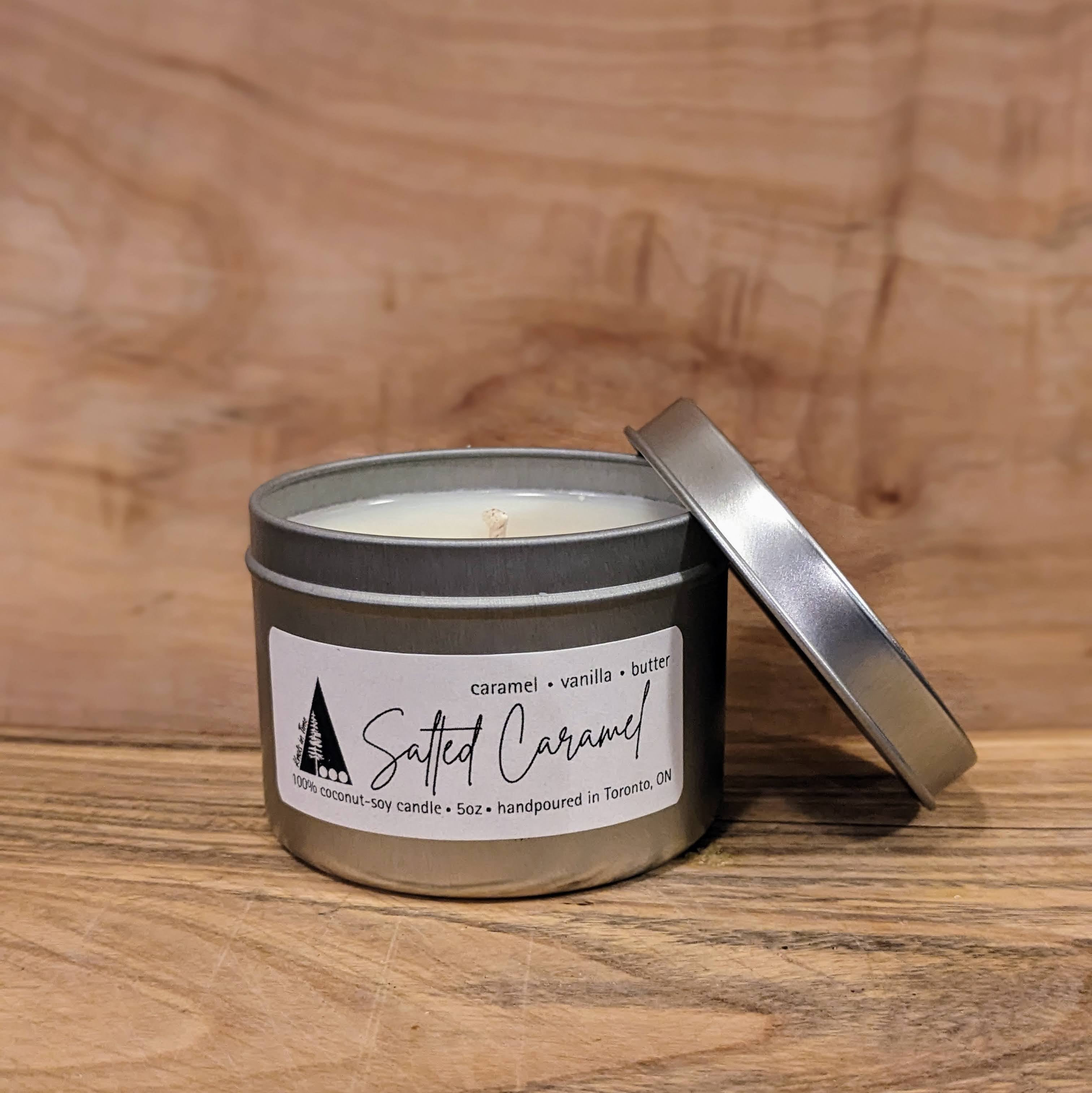 Salted Caramel candle in a metal container on a wooden surface