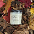 Candle labeled 'Northern Roots' surrounded by autumn leaves