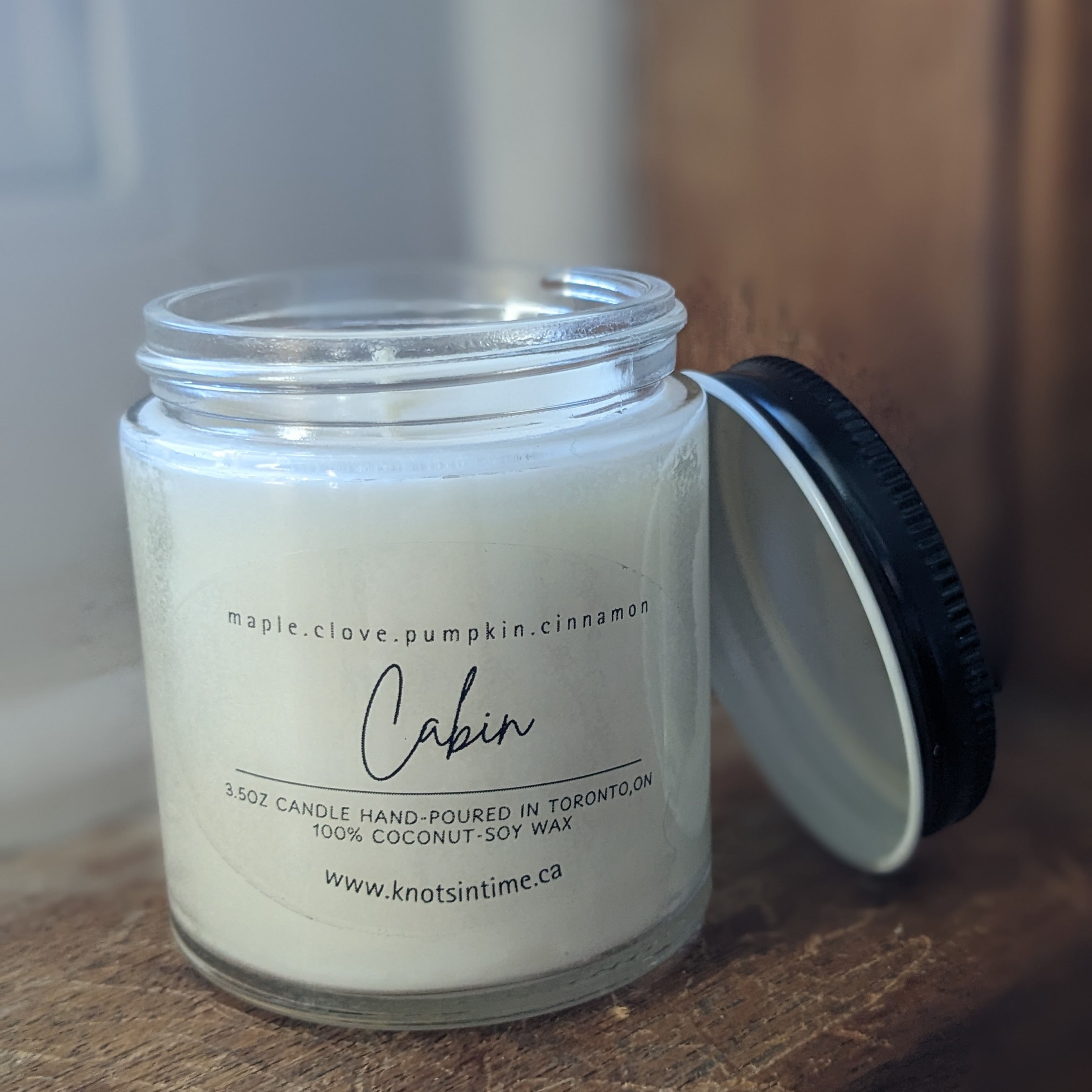 Candle jar with a label on a wooden surface