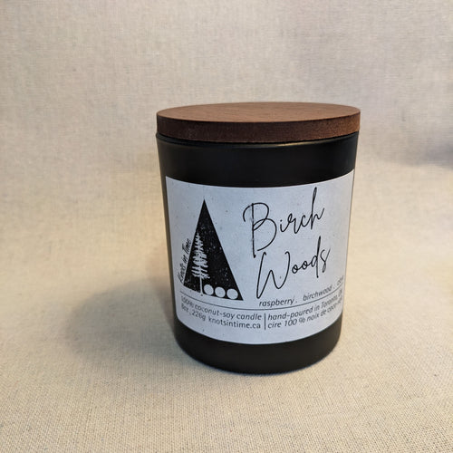 black glass candle with wood lid on a linen texture background