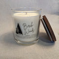 Candle in a glass jar labeled 'Birch Woods' with a wooden lid on a textured surface.