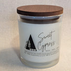 Candle with wooden lid labeled 'Sweet Cypress' on a neutral background