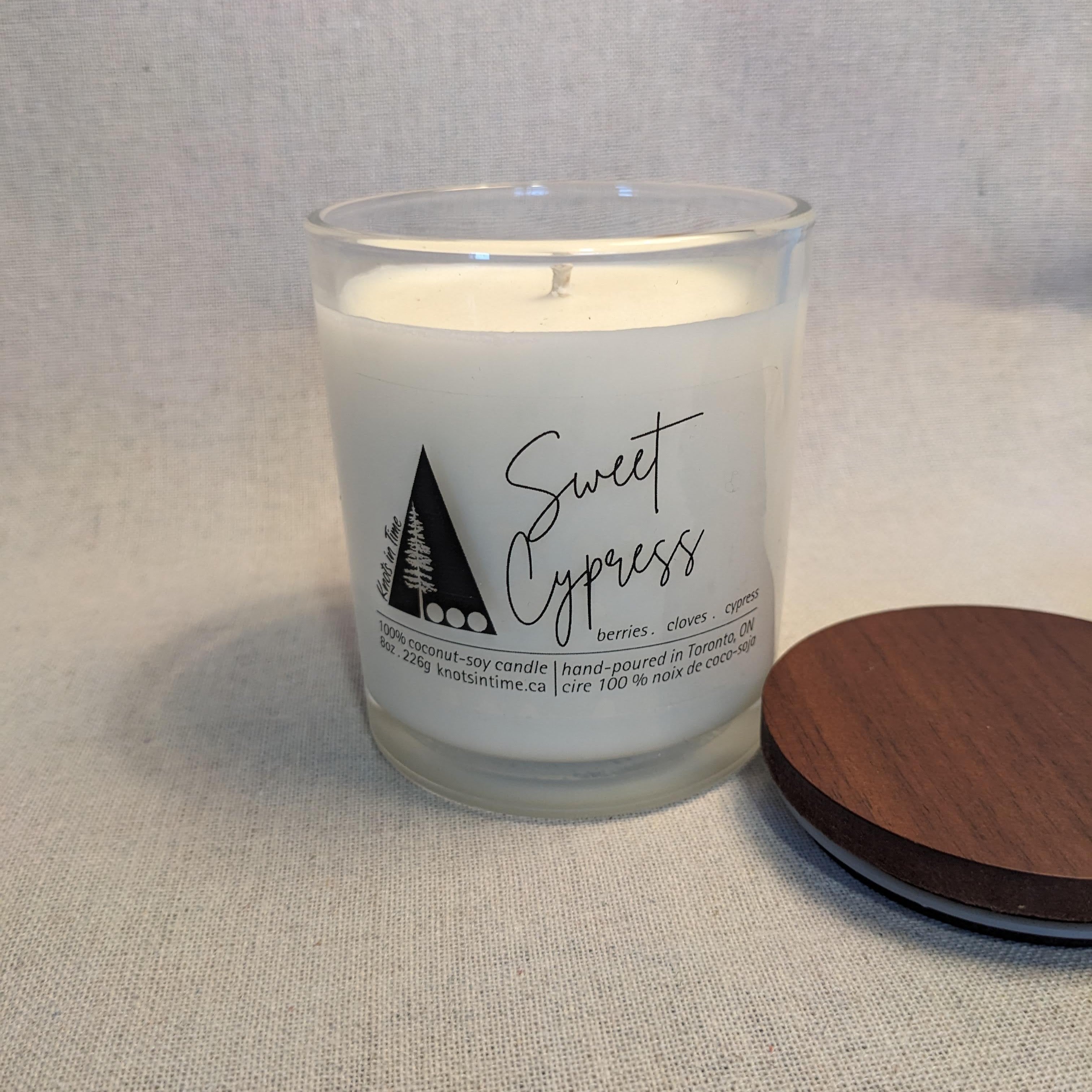 Candle labeled 'Sweet Cypress' with a wooden lid on a neutral background