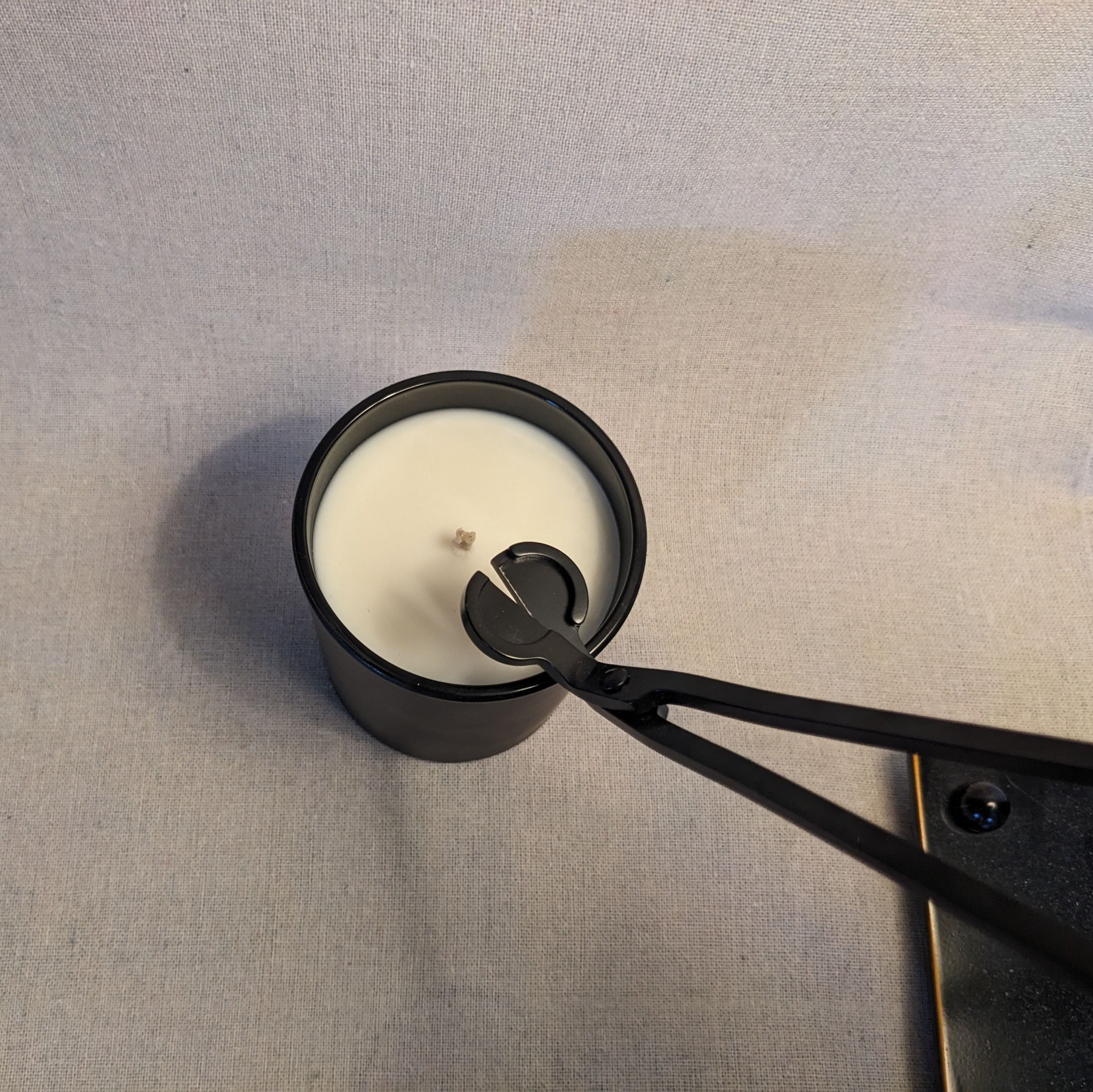 Black candle snuffer with a candle on a gray surface
