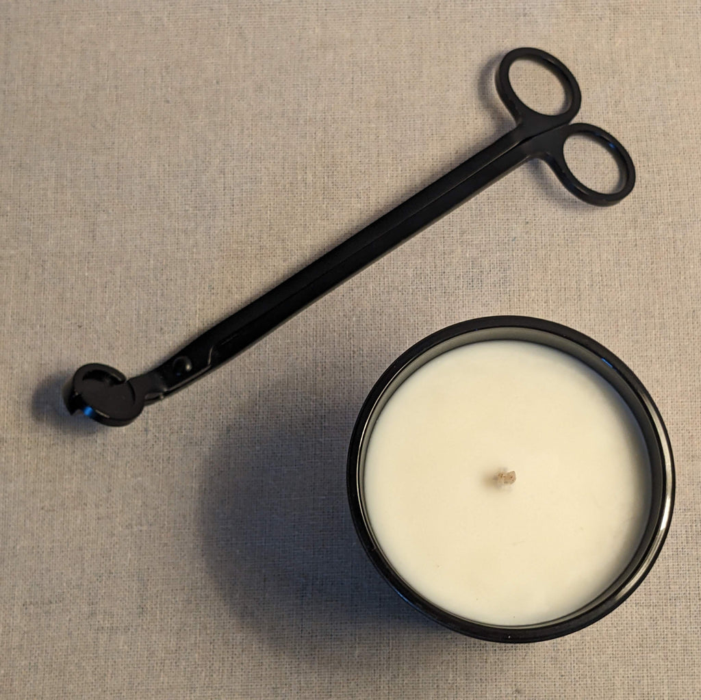 Black candle snuffer and a candle on a linen fabric background