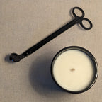 Black candle snuffer and a candle on a linen fabric background