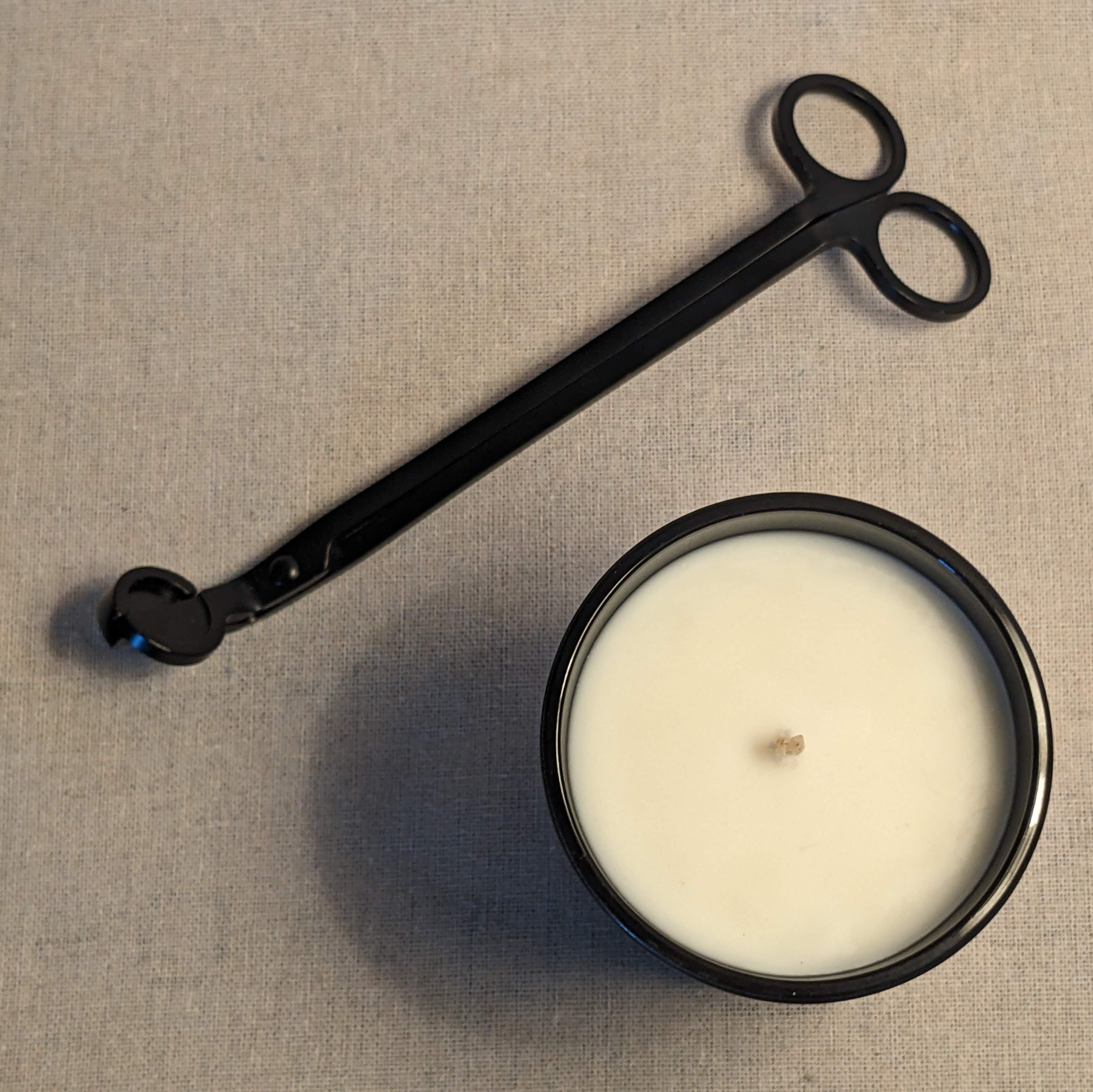 Black candle snuffer and a candle on a linen fabric background