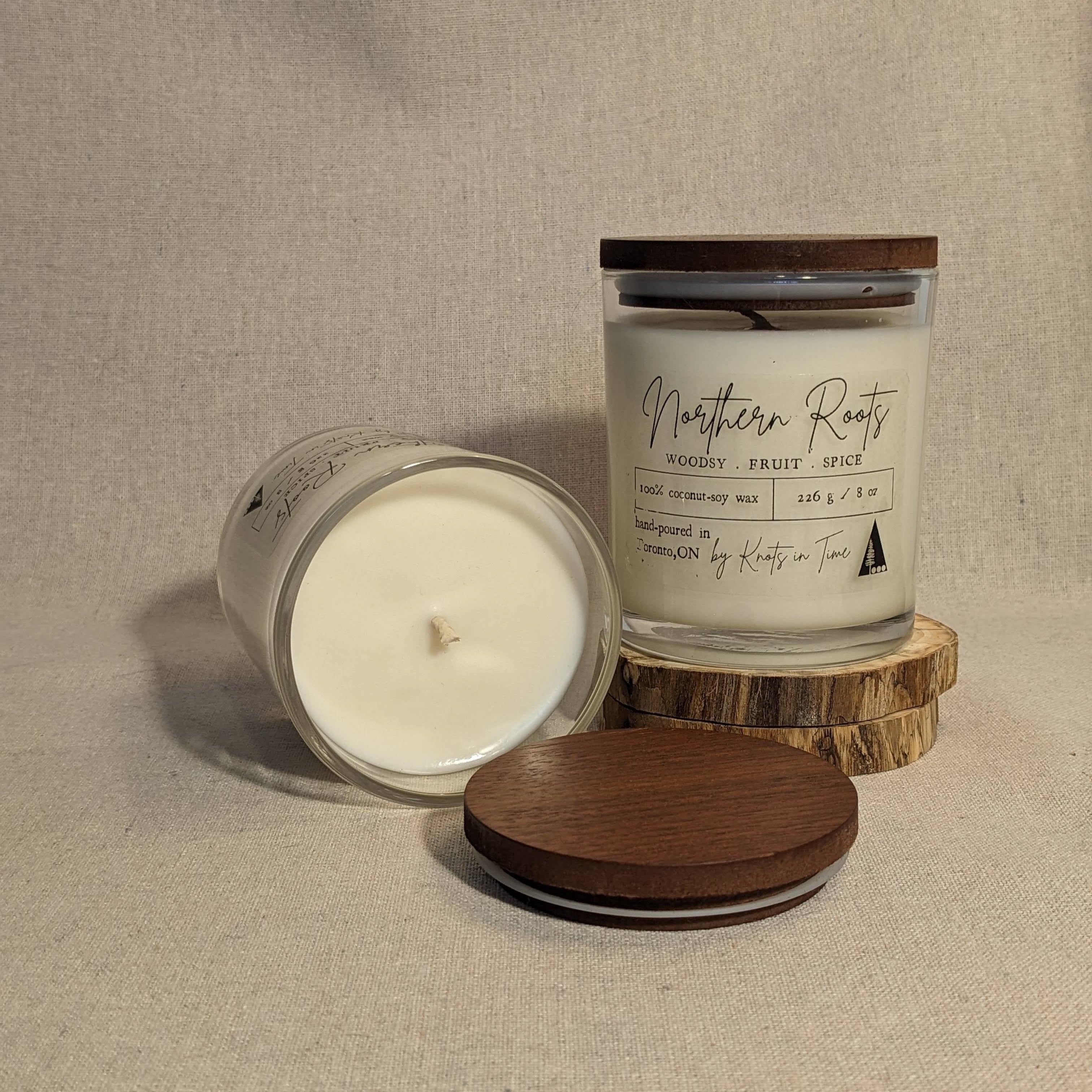 Two candles with wooden lids on a textured surface