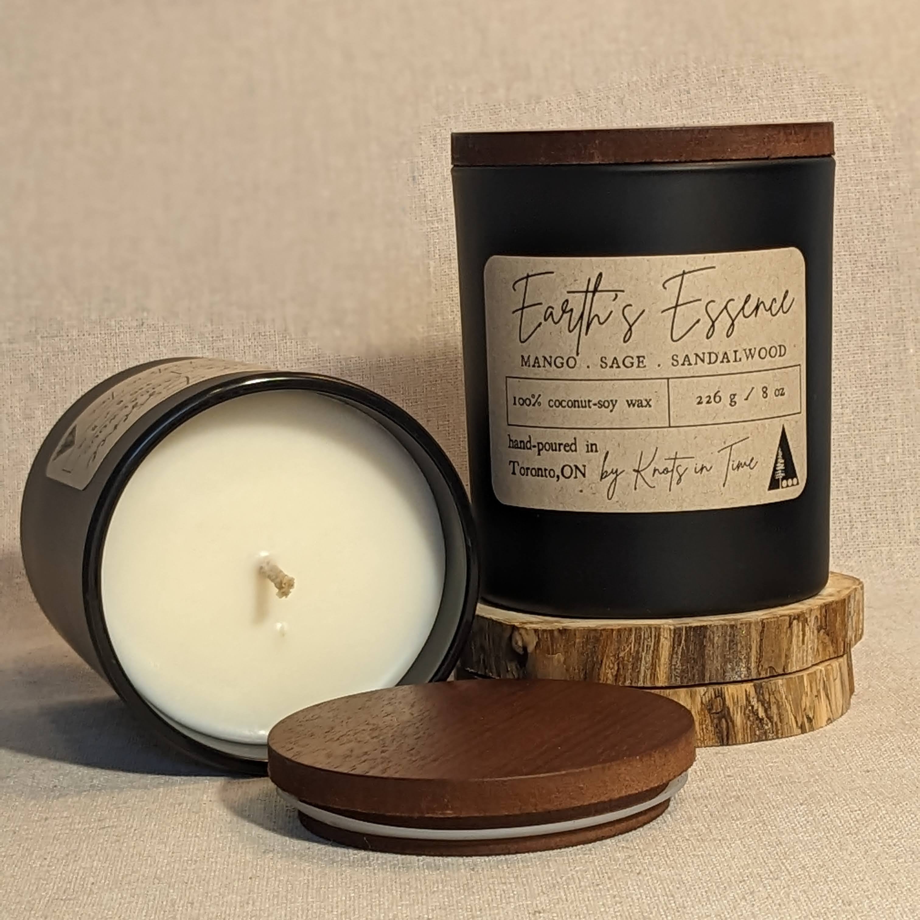 Candle with wooden lid and 'Earth's Essence' label on a beige background