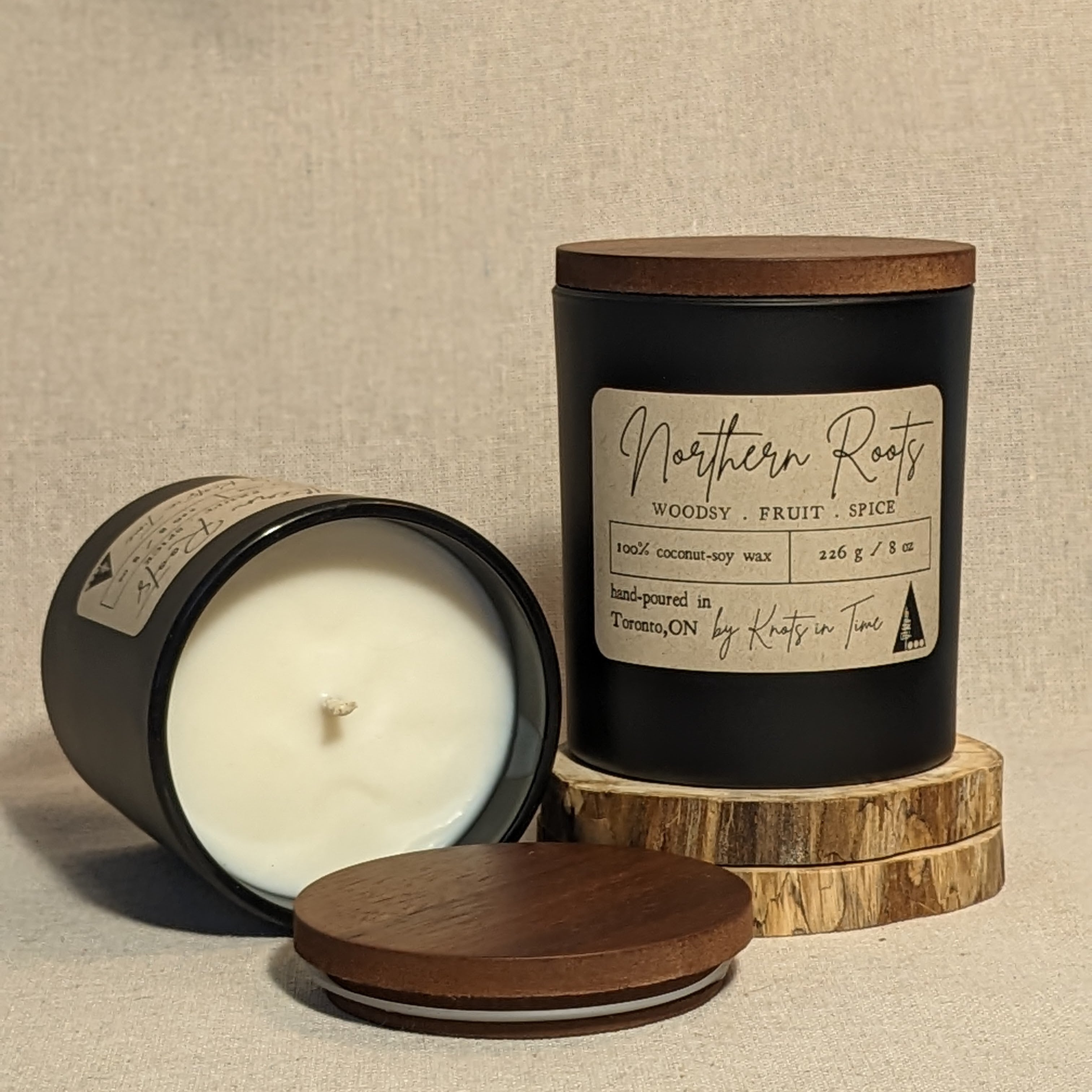 Candle with wooden lid and 'Northern Roots' label on a linen texture background
