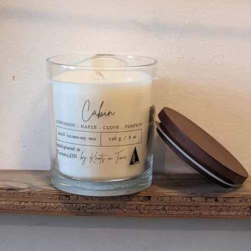 Candle in a glass jar with a label on a wooden surface