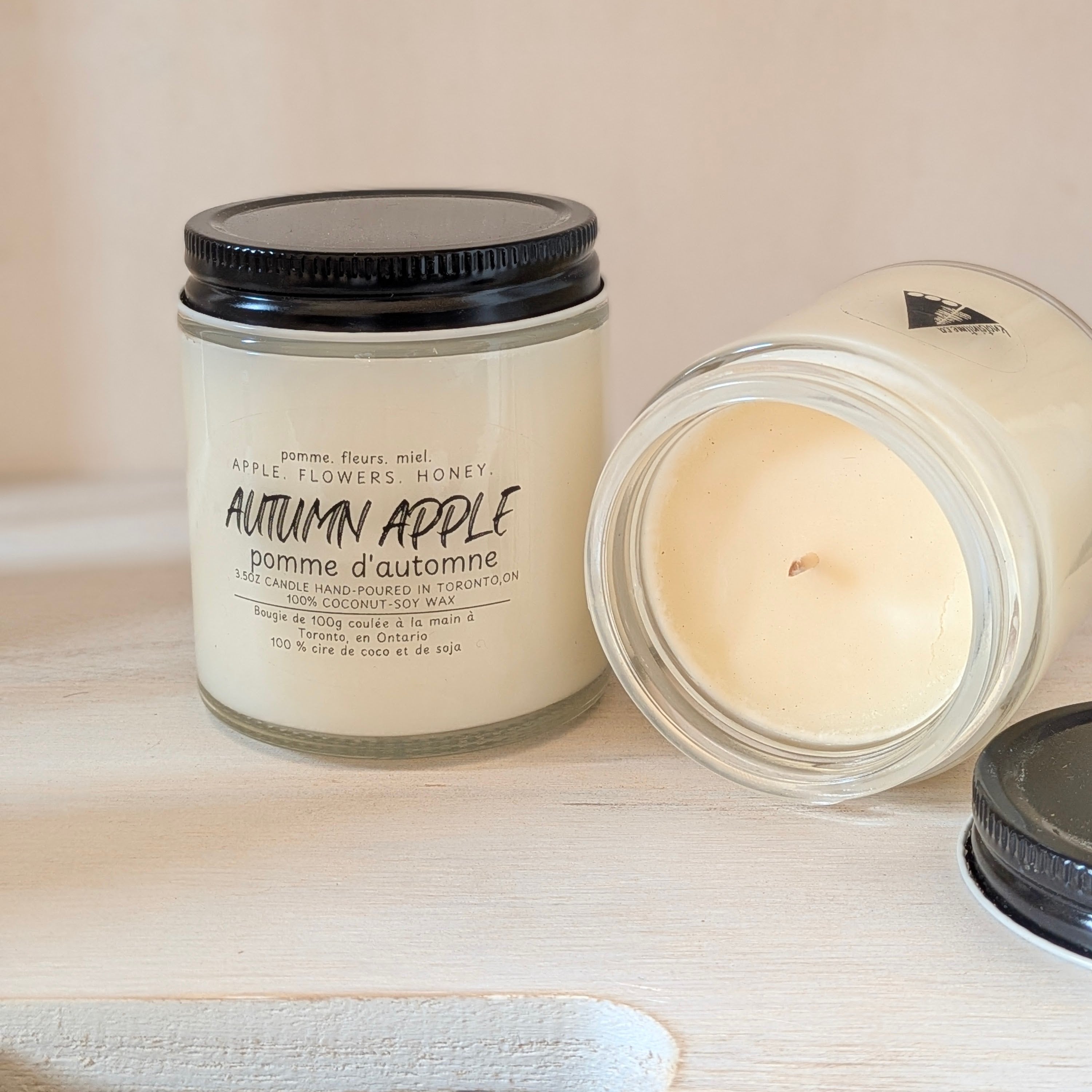 Candle with 'Autumn Apple' label on a wooden surface