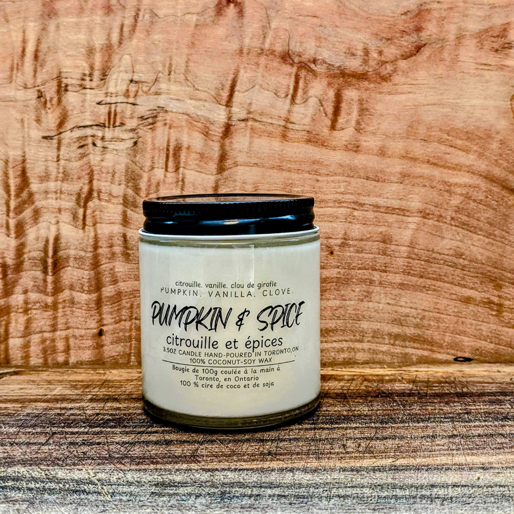 Candle labeled 'Pumpkin & Spice' on a wooden surface