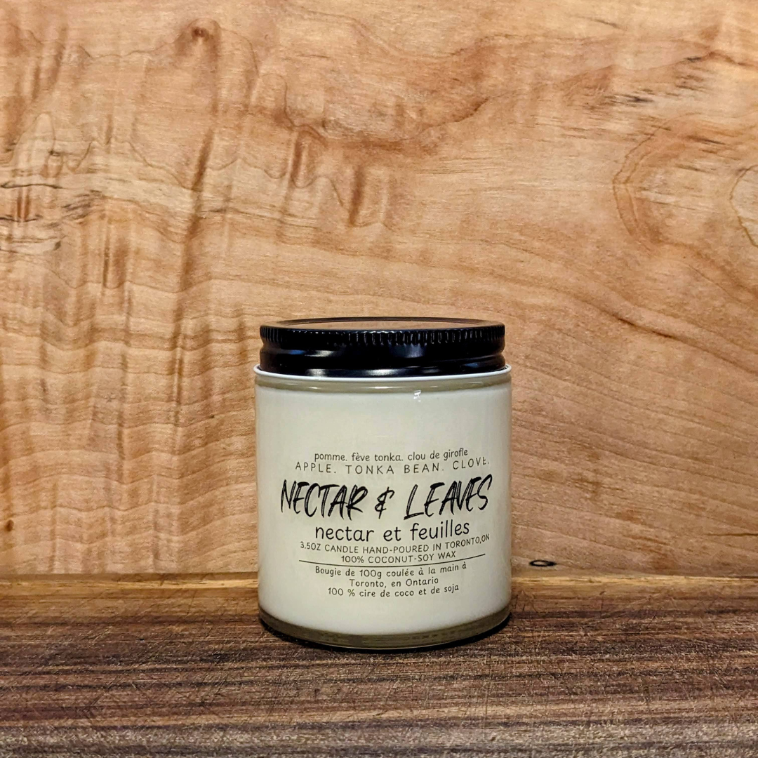 Candle jar labeled 'Nectar & Leaves' on a wooden surface