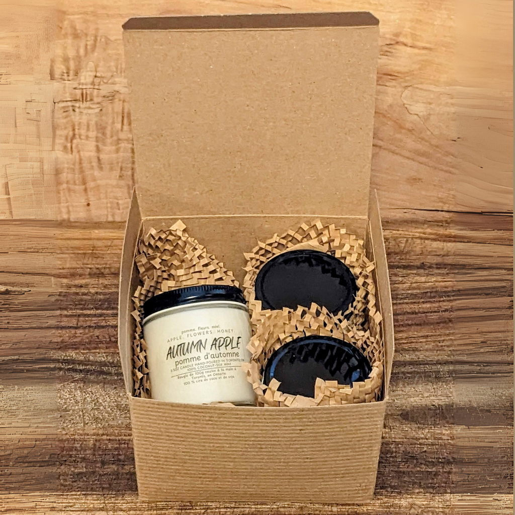 Gift set with three candles in a brown box on a wooden surface