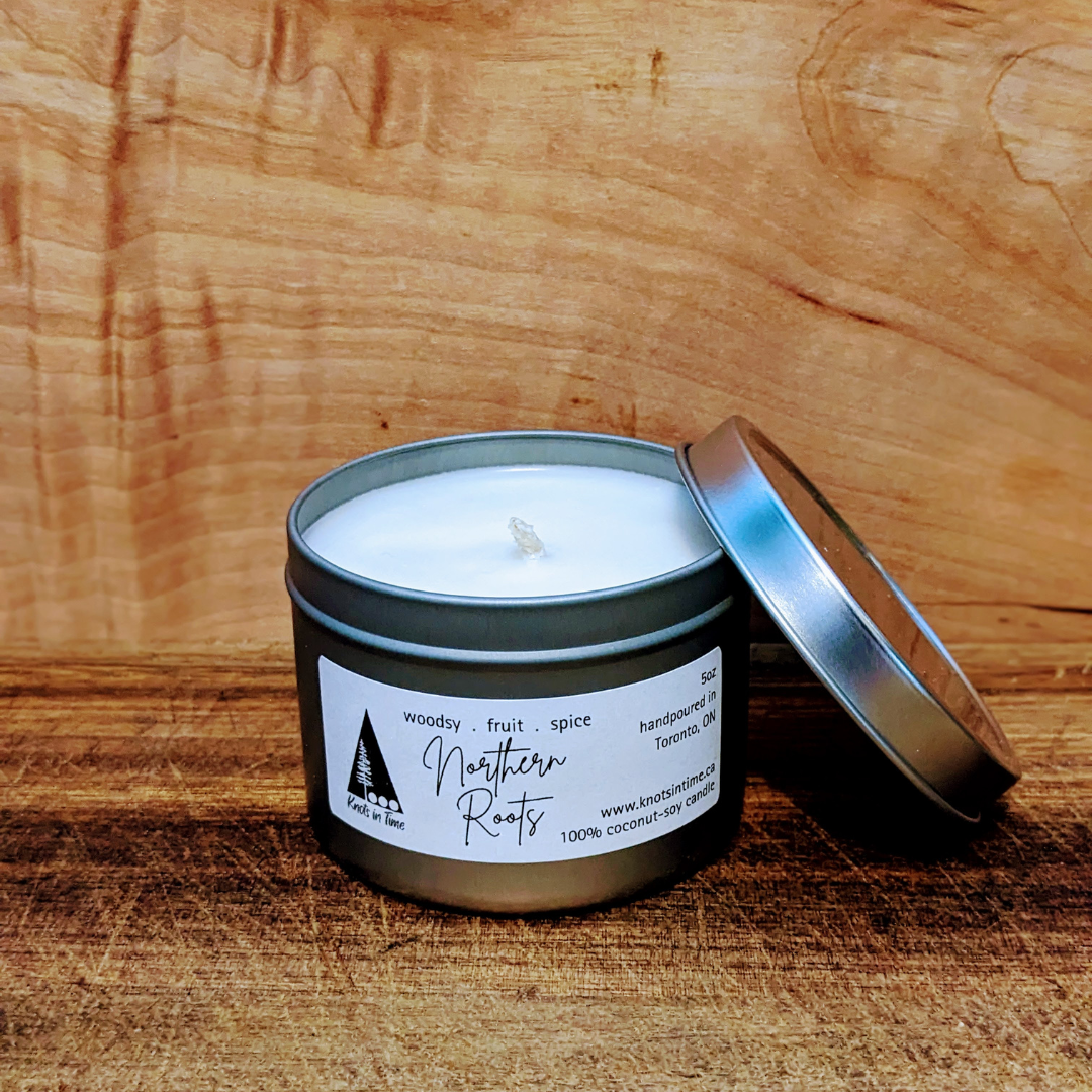 Candle in a metal tin with a label on a wooden surface