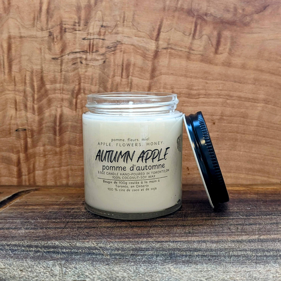 Candle labeled 'Autumn Apple' on a wooden surface