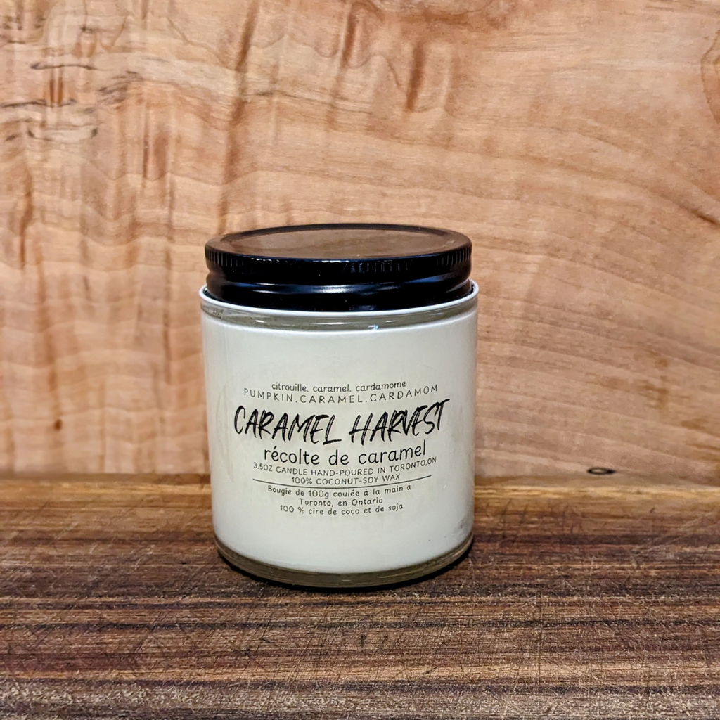 Candle jar labeled 'Caramel Harvest' on a wooden surface