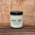 Candle jar labeled 'Caramel Harvest' on a wooden surface