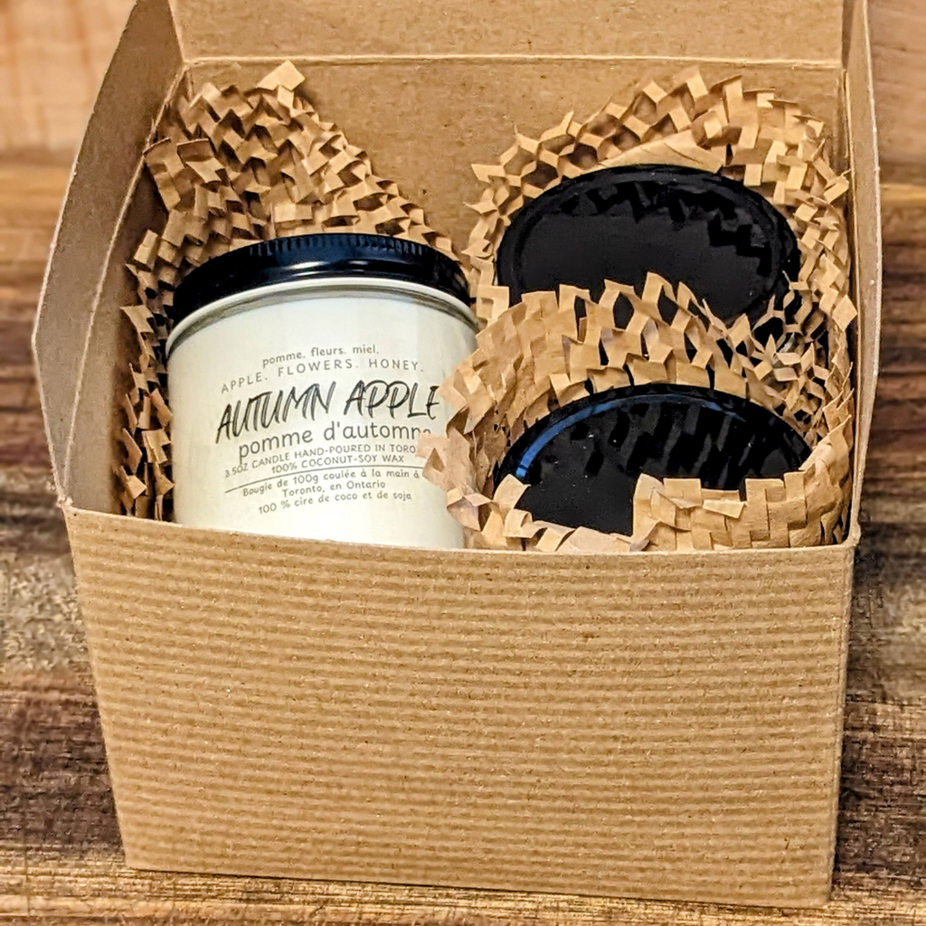 Three candles in a decorative box with woven paper. 
