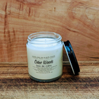 Candle labeled 'Cider Woods' on a wooden surface