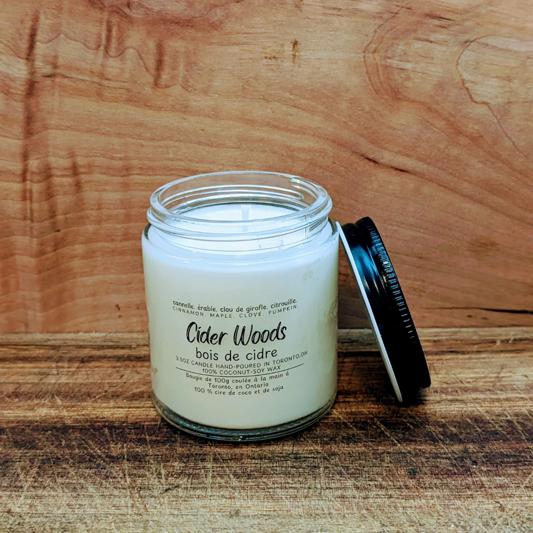Candle labeled 'Cider Woods' on a wooden surface