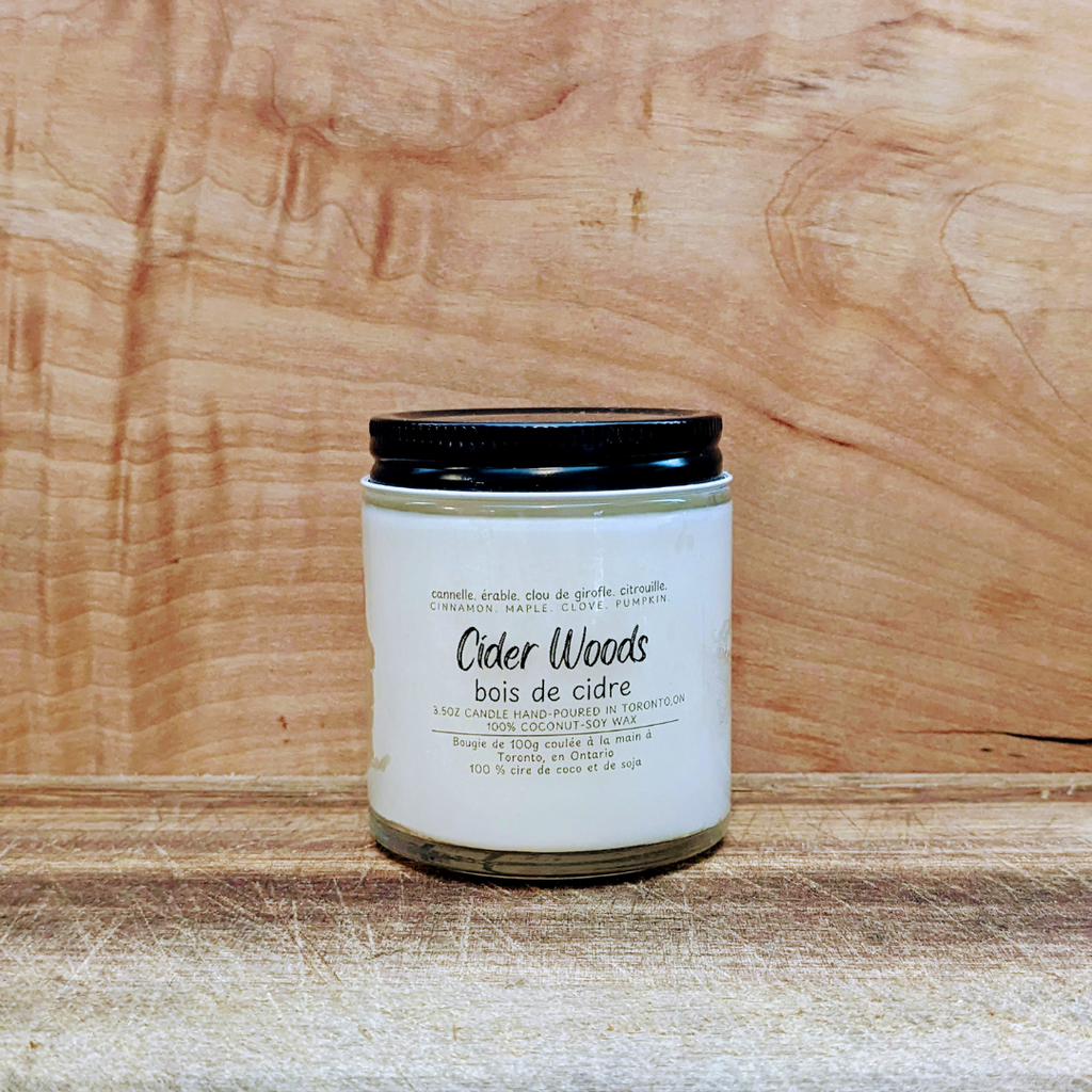 Candle labeled 'Cider Woods' on a wooden surface