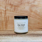 Candle labeled 'Cider Woods' on a wooden surface