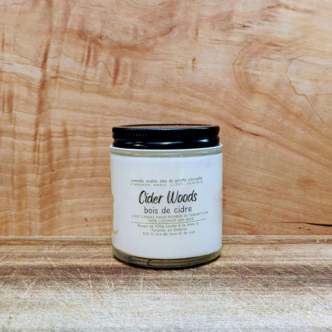 Candle labeled 'Cider Woods' on a wooden surface
